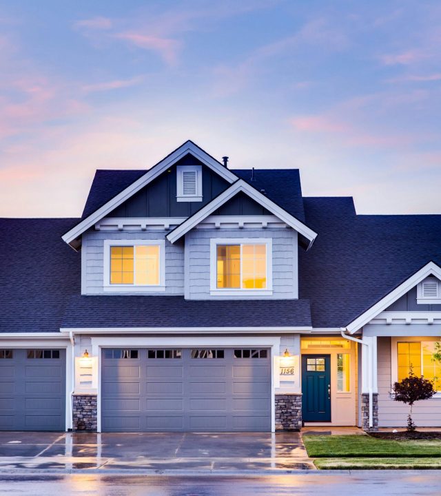 Beautiful two-story house with illuminated windows and garage at dusk.